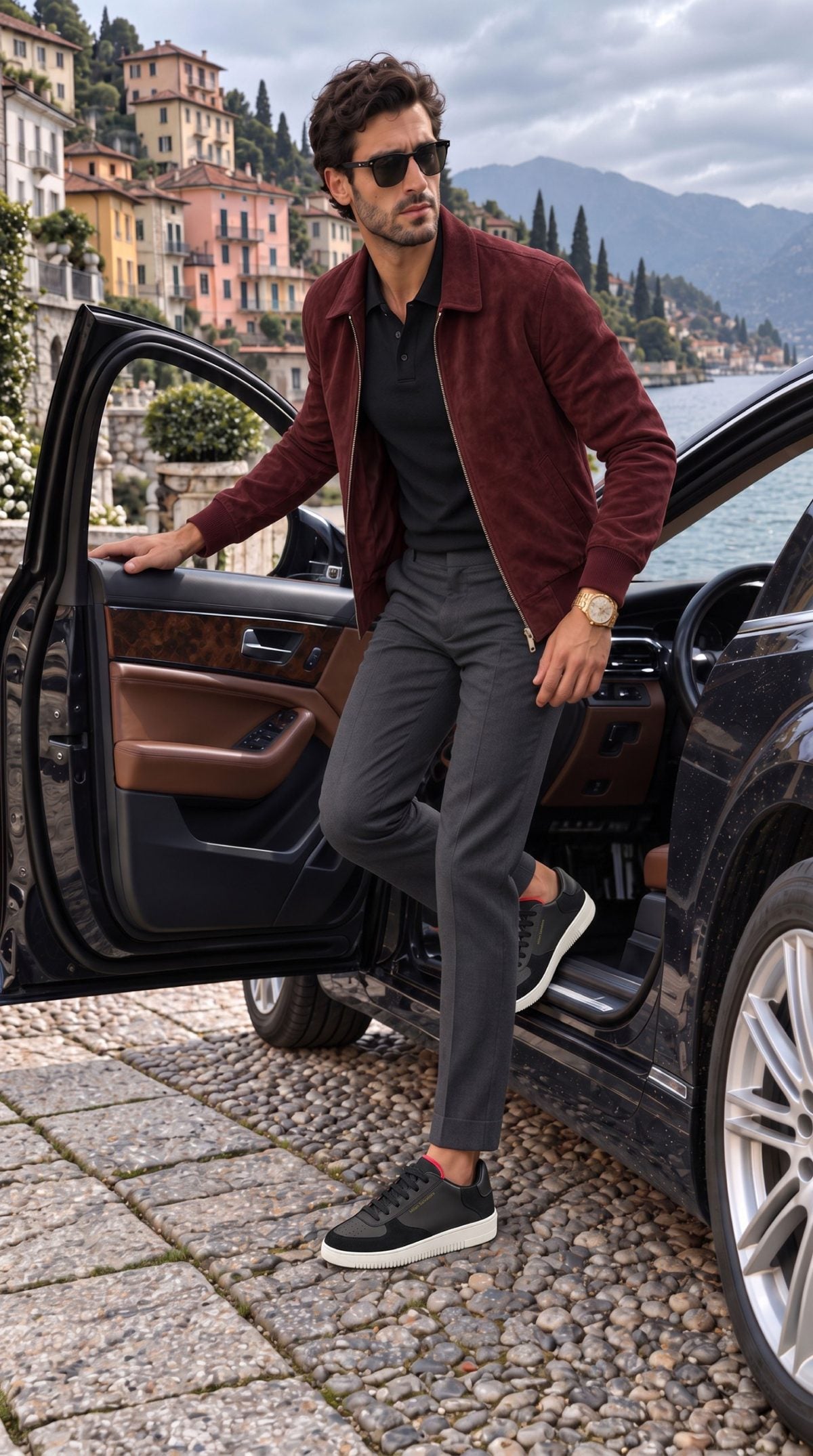 A man in a burgundy suede jacket and grey trousers stepping out of a car on Lake Como, wearing the Nero Bold