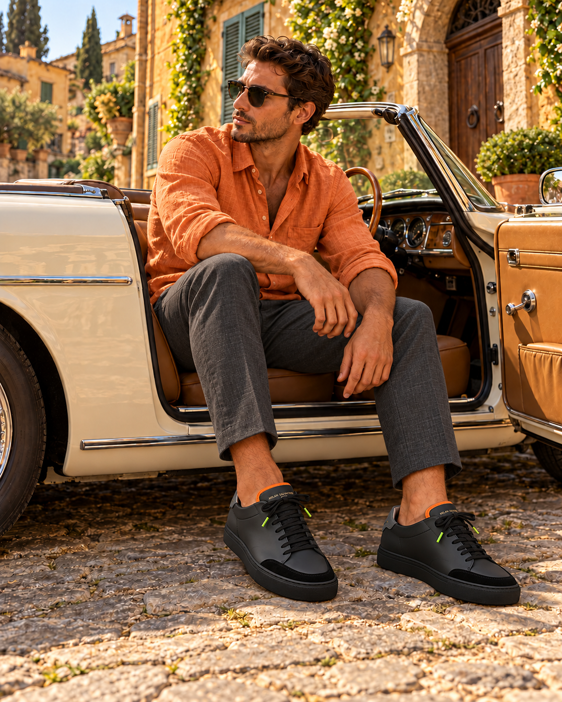 A man in a rust linen shirt and charcoal trousers seated in a vintage convertible, wearing the Nero Everyday
