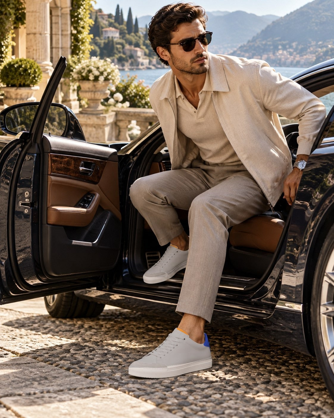A man in a cream jacket and linen trousers stepping out of a car on the Italian lakes, wearing the Grigio Everyday